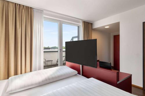 a hotel room with a bed and a flat screen tv at Amedia Linz, Trademark Collection by Wyndham in Linz