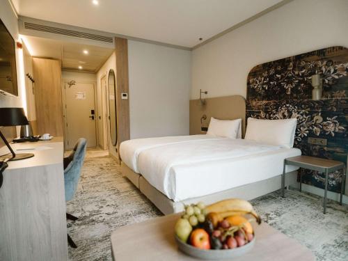 a hotel room with a bed and a bowl of fruit on a table at Mercure Sibiu Arsenal in Sibiu