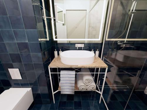 ein Bad mit einem Waschbecken und einem Spiegel in der Unterkunft Mercure Sibiu Arsenal in Sibiu