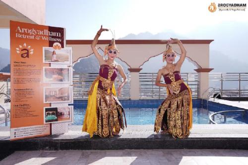 two women in costumes standing next to a swimming pool at Arogyadham Wellness Retreat in Rishīkesh
