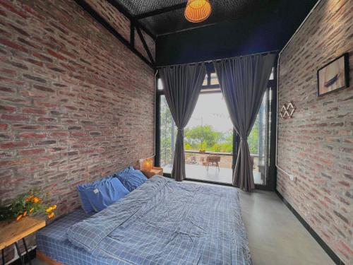 um quarto com uma cama numa parede de tijolos em Vườn Trên Mây - Skyline Farm & Homestay em Mộc Châu