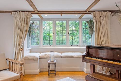 a living room with a piano and windows at The Little House in Thatcham