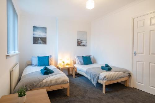 2 camas en una habitación con almohadas azules en 2Bed-Free Parking-EV Charger en Wishaw