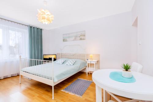 a white bedroom with a bed and a table at Willa Muszelka Przy Morzu in Jastarnia