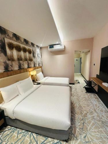 a bedroom with a large white bed and a tv at SKY PARK HOTEL in Dubai