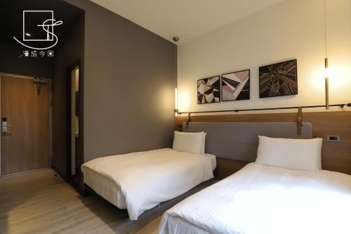 two beds in a hotel room with two beds sidx sidx sidx at Slow Town Hotel-Konkai in Tainan
