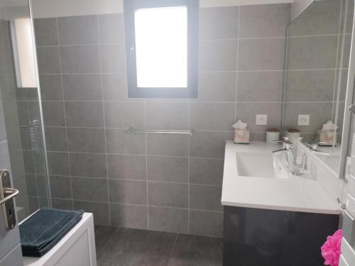 une salle de bain avec un lavabo et une douche avec une fenêtre dans l'établissement villa avec jacuzzi, à Malaucène