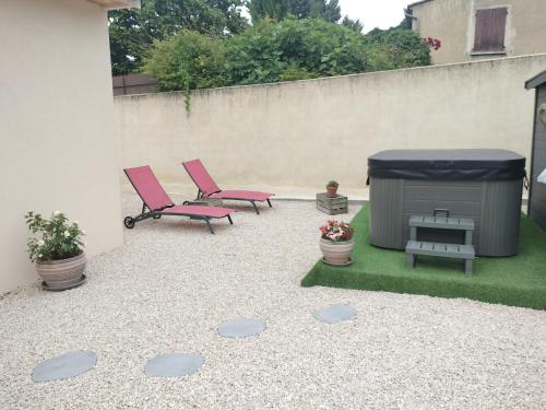 une terrasse avec 2 chaises roses et un grill dans l'établissement villa avec jacuzzi, à Malaucène