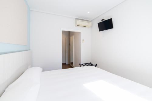 um quarto com uma cama branca e uma televisão em Hotel Alkazar em Valência
