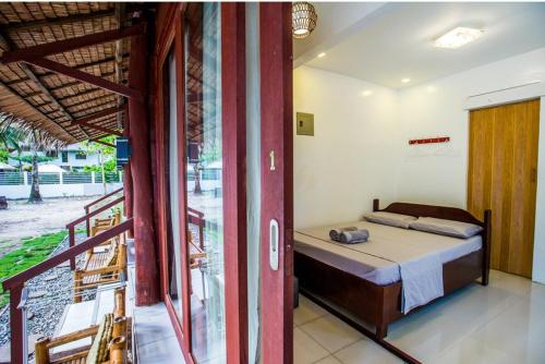 1 dormitorio con 1 cama y balcón en Villa Gumamela Siargao, en Catangnan