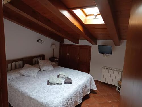 a bedroom with a bed with a white comforter and a television at Turismo Rural Calaliu in Peratallada