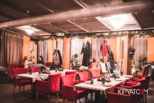 a dining room with tables and red chairs and people at Mildom Premium Hotel in Almaty
