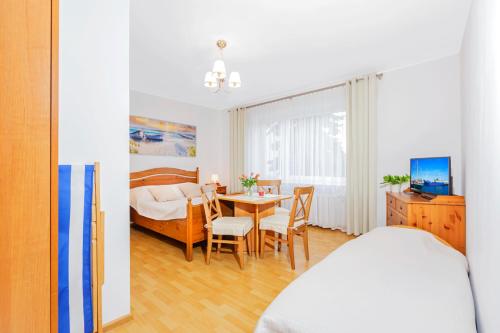 a bedroom with a bed and a table with chairs at Willa Muszelka Przy Morzu in Jastarnia