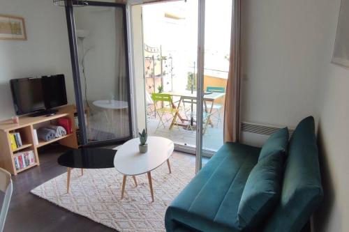 un salon avec un canapé vert et une table dans l'établissement Joli T2 à 10min à pied du village, parking, vue dégagée, résidence au calme, à Collioure