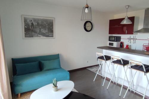 sala de estar con sofá azul y cocina en Joli T2 à 10min à pied du village, parking, vue dégagée, résidence au calme, en Collioure