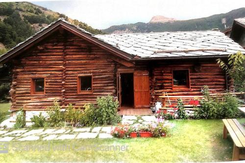 a log cabin with flowers in front of it at Magnificent spacious 4 bedroom mountain chalet with spa in Antey-Saint-André