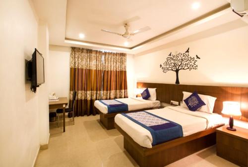 a hotel room with two beds and a television at Rainbow International Hotel Airport Zone Shamshabad in Shamshabad