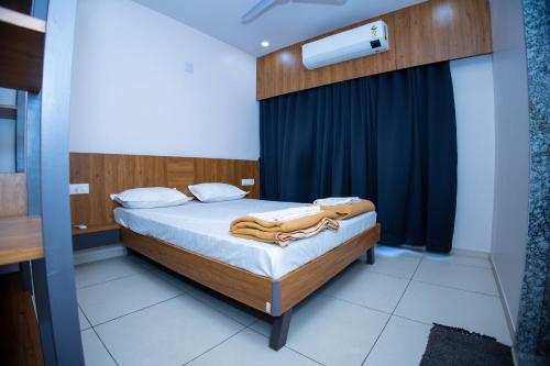 1 dormitorio con 1 cama con cortina azul en 24 CARAT STUDIO APARTMENTS en Porbandar
