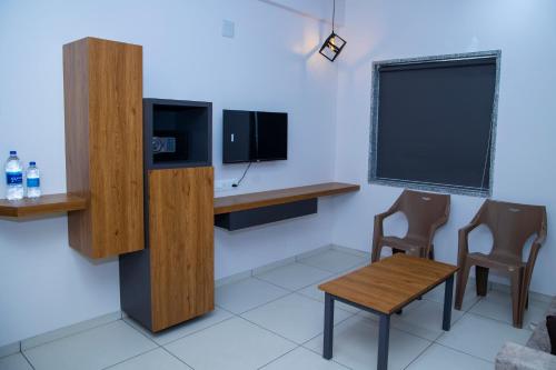 Zimmer mit einem Schreibtisch, einem TV und 2 Stühlen in der Unterkunft 24 CARAT STUDIO APARTMENTS in Porbandar
