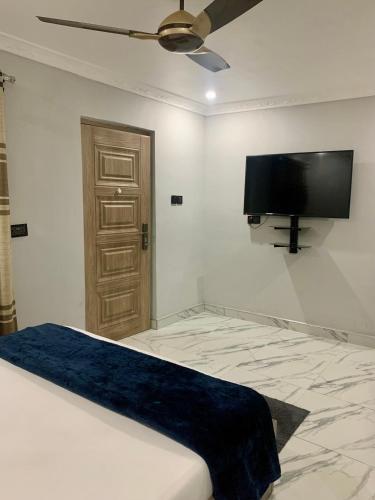 Schlafzimmer mit einem Bett und einem Flachbild-TV an der Wand in der Unterkunft Mnc Homes Akrowa house in Labadi