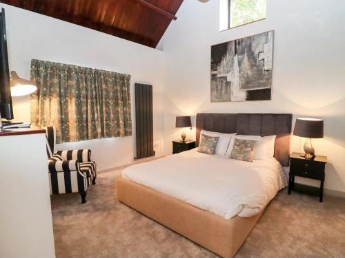 a bedroom with a large bed and a chair at Mayfield Cottage in Malmesbury