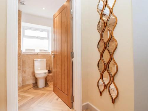 La salle de bains est pourvue de toilettes et d'une porte en bois. dans l'établissement Mayfield Cottage, à Malmesbury