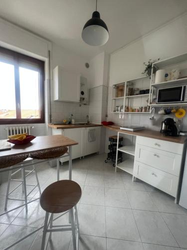 cocina con armarios blancos, mesa y sillas en The 6th floor flat - direct link to centre in 8 mins en Milán