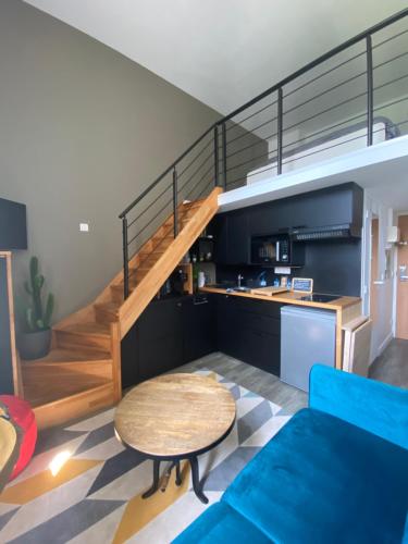 - un salon avec un canapé bleu et un escalier dans l'établissement Une fenêtre sur l océan, Studio duplex dans résidence de standing avec piscine et vue sur mer, au Croisic