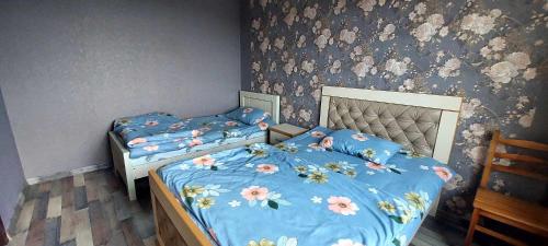2 aparte bedden in een slaapkamer met bloemenbehang bij Guest House Godogani in Godogani