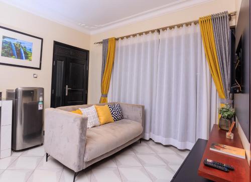 ein Wohnzimmer mit einem Sofa und einem TV in der Unterkunft Greenwoods Apartments in Kampala