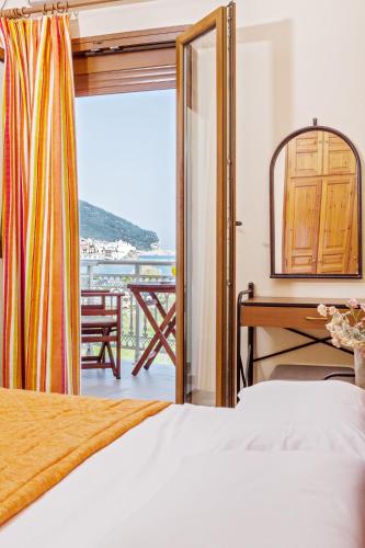 a bedroom with a bed and a desk and a balcony at MON REPOS in Panormos Skopelos