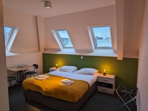 a bedroom with a bed with three windows and two tables at Hotel 1851 in Wijk bij Duurstede