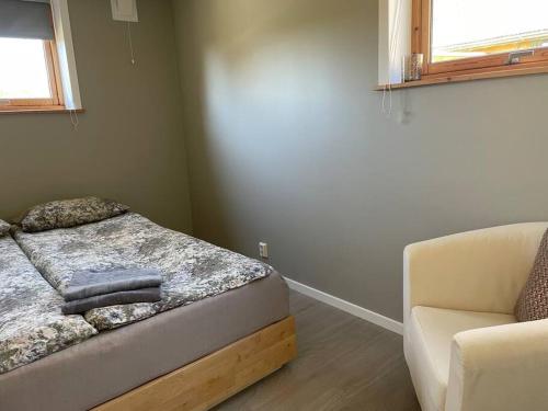 a bedroom with a bed and a couch and a chair at Cozy ground floor apartment in nature, by driving 300 metres of gravel road on top of the hill in Lunde
