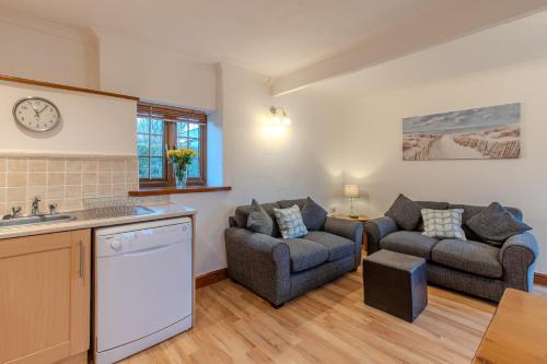 cocina y sala de estar con sofá y silla en Elidir Cottage en Llanfairpwllgwyngyll