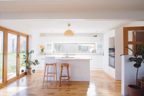 a kitchen with a white counter and two stools at Scandi Style Home away from Home In Newquay in Newquay