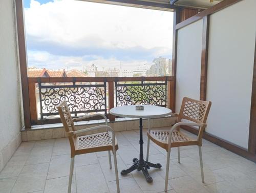 einen Balkon mit einem Tisch und Stühlen sowie einem großen Fenster in der Unterkunft Hotel Happy in Gjakove