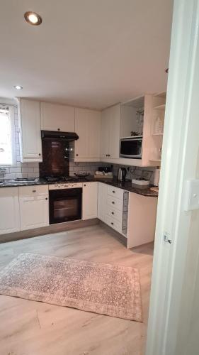 a kitchen with white cabinets and a rug on the floor at Cozy Cabin in Midrand