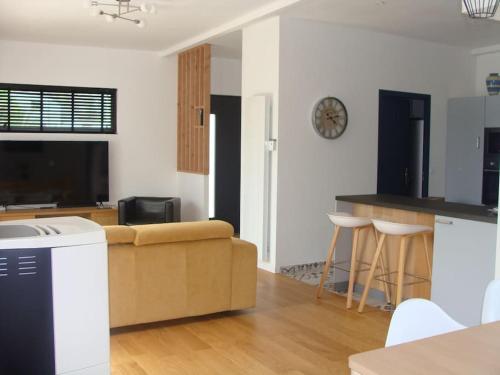 ein Wohnzimmer mit einem Sofa und einer Küche in der Unterkunft Maison moderne pour 4- 5 personnes in Sulniac
