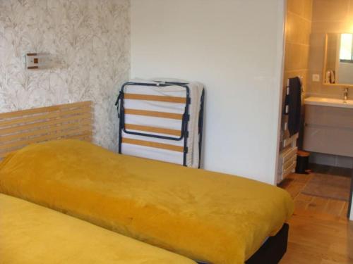 ein Bett mit einer gelben Decke in einem Zimmer in der Unterkunft Maison moderne pour 4- 5 personnes in Sulniac