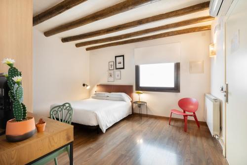 a bedroom with a white bed and a red chair at Hostal Pichorradicas in Tudela