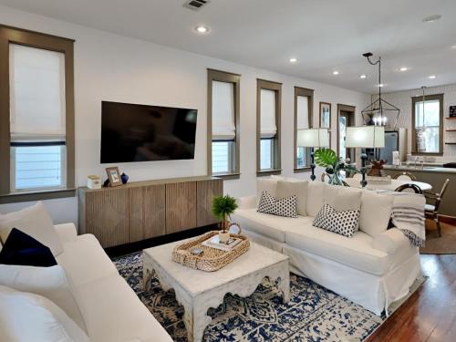 a living room with white furniture and a flat screen tv at The Holland House II in Rosemary Beach