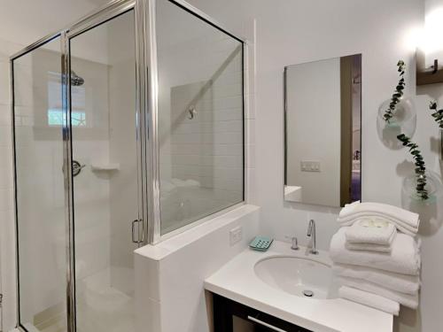 a white bathroom with a shower and a sink at The Holland House II in Rosemary Beach