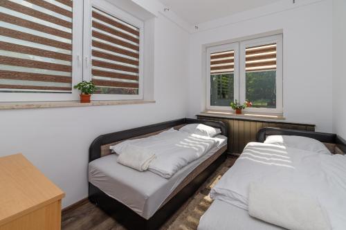 two beds in a room with two windows at Koma Vendégház in Aporliget