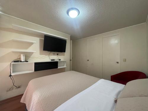 1 dormitorio con 1 cama blanca y TV en Panoramic Aparment San Miguel en Lima