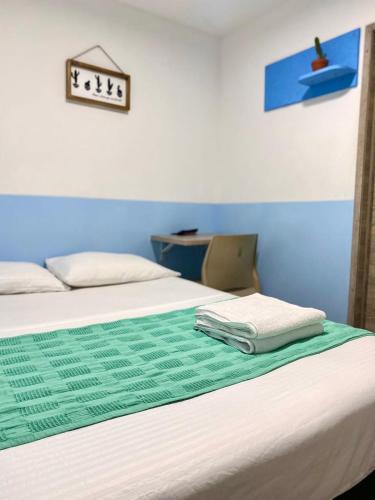 a bedroom with a bed with a green and white blanket at Hotel Anauco in Bucaramanga