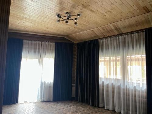 a room with two windows with curtains and a chandelier at Hotel Ashad in Svalyava
