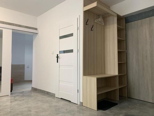 a closet with a white door and wooden shelves at Apartamenty Św.Rocha in Białystok