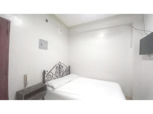 une chambre blanche avec un lit et un haut-parleur dans l'établissement OYO 1066 Dorotello Apartelle, à Manille