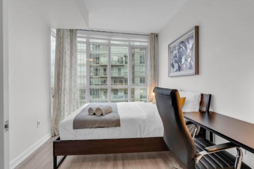 een slaapkamer met een bureau, een bed en een raam bij Spadina Modern suites in Toronto