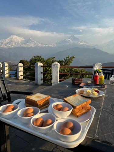 a tray of food on a table with mountains in the background at Club ES Deurali Resort in Pokhara